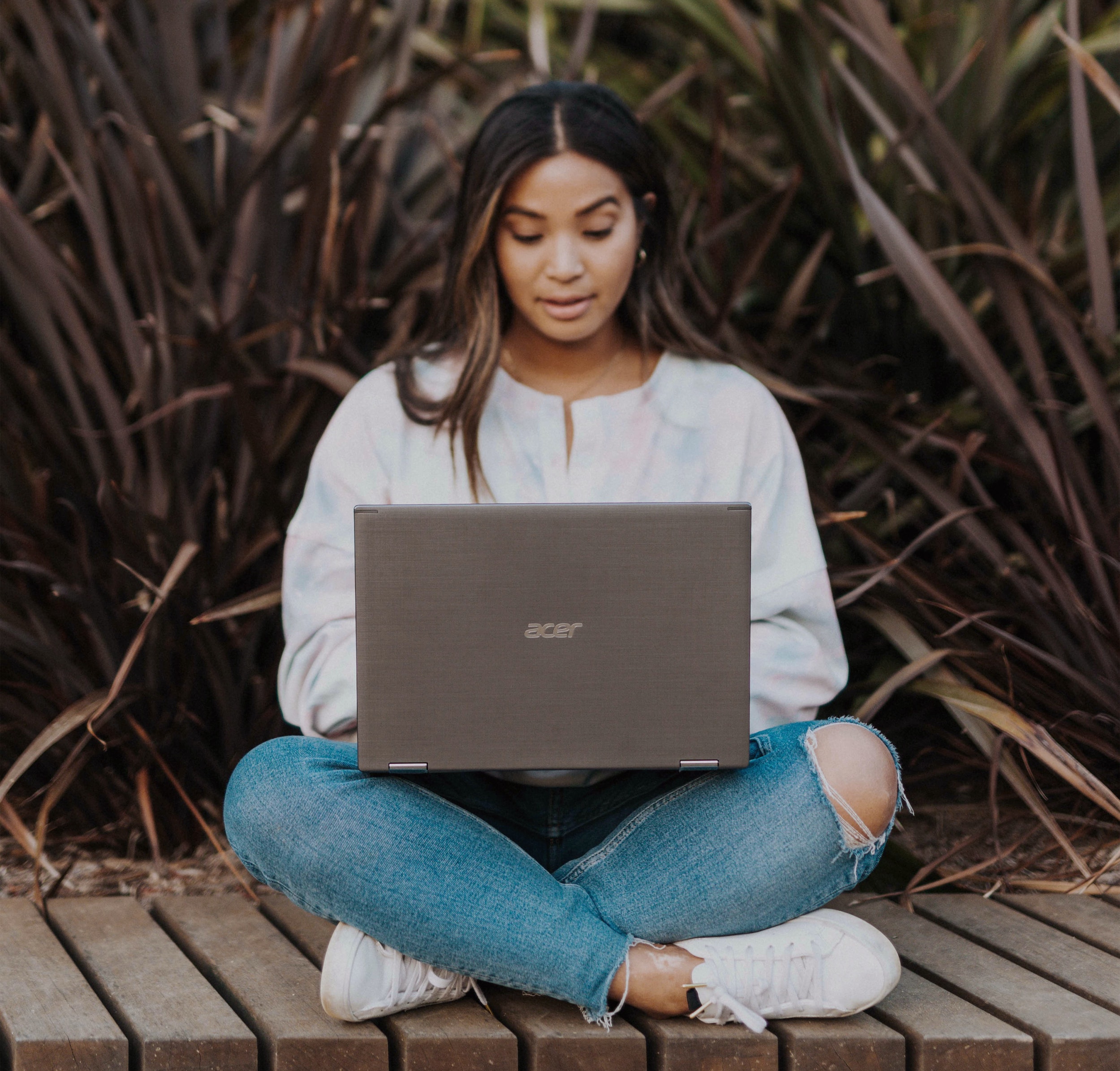 A woman in casual clothes using a laptop outside